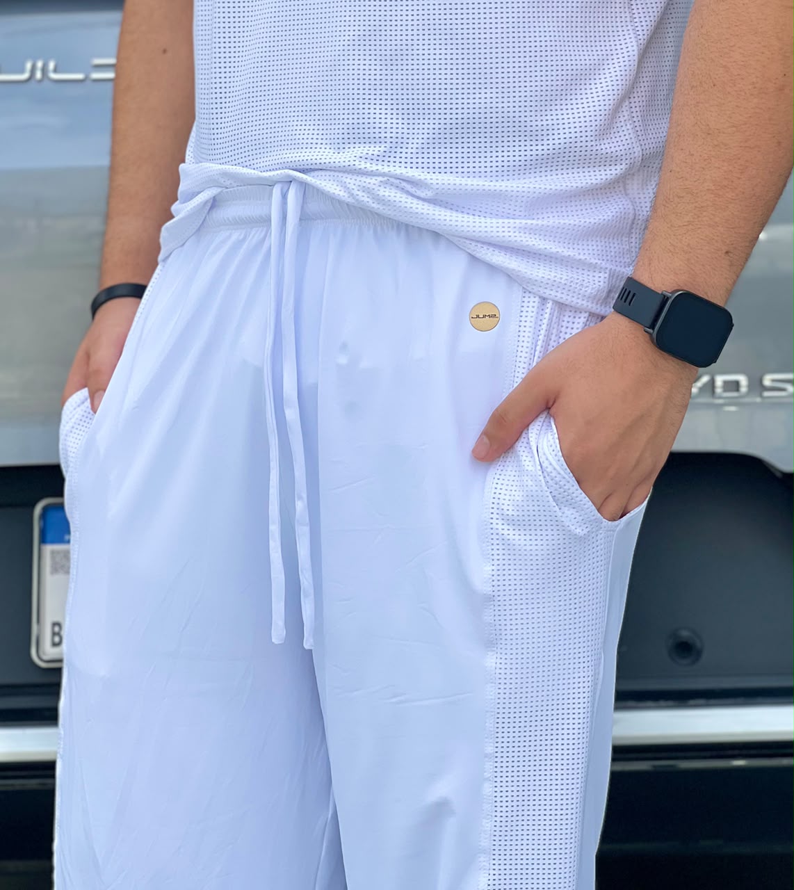 Detalhe do cós, cordão e selo dourado da calça masculina branca — Jump Modas